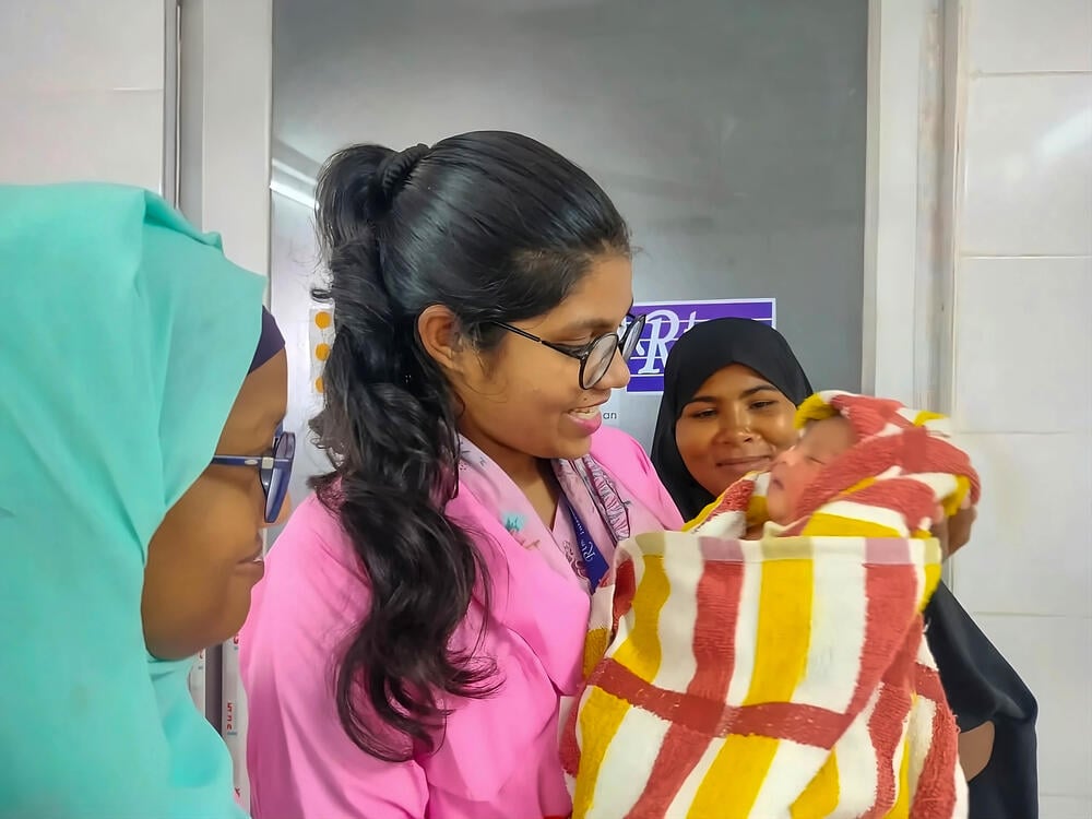 From left to right: Tamanna Jahan, Arafin Mim, and the baby’s mother gaze at a newborn they helped safely deliver.